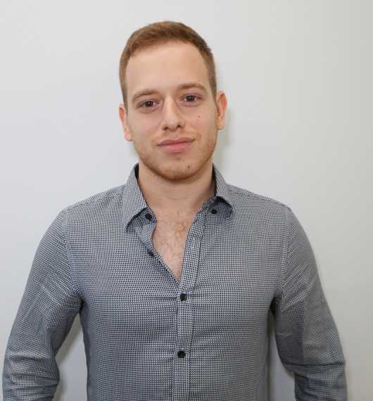 Young man with short light brown hair wearing a black and white checkered shirt against a plain white background.