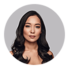 Portrait of a woman with long dark hair and a neutral expression against a gray background.